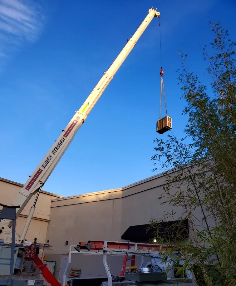 HVAC system being lifted by machinery onto a roof for installation, representing professional air conditioner, AC, air conditioning, cooling, furnace, heating, heater services, including repair, maintenance, tune up, installation, replacement, and upgrade by Smith & Sons Heating and Air. We provide AC repair, air conditioner repair, air conditioning service, cooling system maintenance, furnace repair, heating system tune up, heater installation, HVAC maintenance, air conditioning installation, furnace replacement, heating system upgrade, AC maintenance near me, air conditioner tune up near me, cooling repair near me, furnace service near me, heater repair near me, HVAC installation near me, heating repair near me, air conditioning upgrade near me, furnace tune up near me, heater replacement near me, HVAC repair near me.